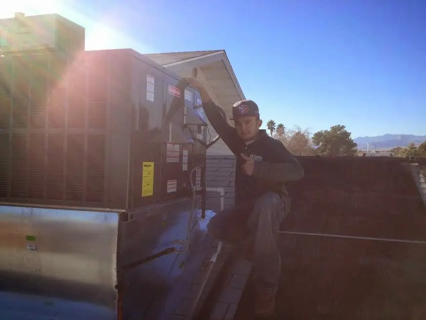 HVAC technician performing Air Duct Cleaning on a rooftop unit in Maricopa
